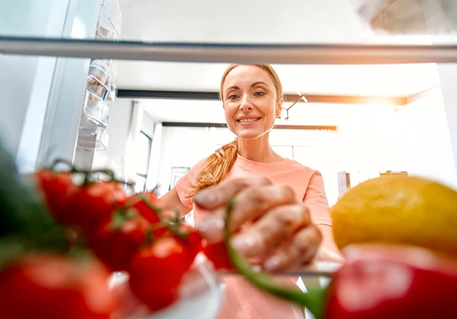 Frau greift in Kühlschrank Vitamin-C-Lebensmittel im Kühlschrank