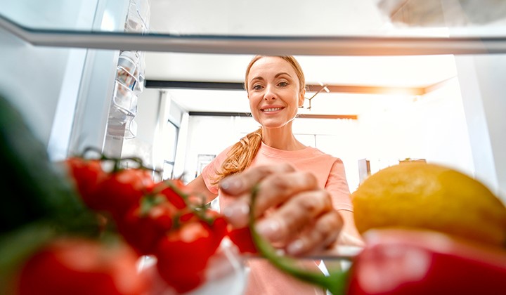 Frau greift in Kühlschrank Vitamin-C-Lebensmittel im Kühlschrank